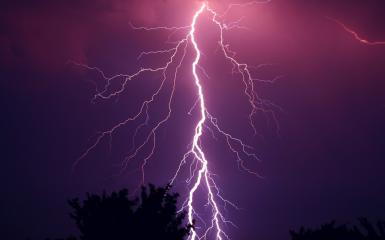 Obraz przedstawia uderzający w ziemię piorun