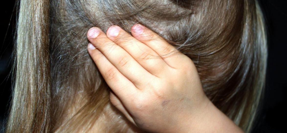  Dziewczynka zakrywająca ręką ucho