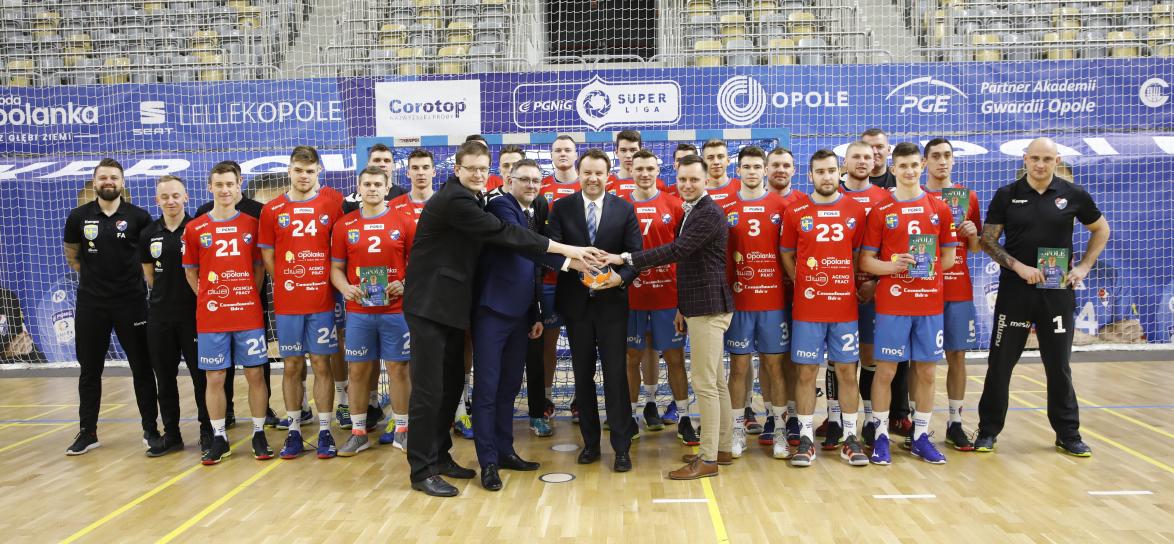 Zdjęcie zawodników i działaczy Gwardii Opole stojących przy bramce z prezydentem Arkadiuszem Wiśniewskim, Przemysławem Zychem i naczelnikiem wydziału sportu - Marcinem Saganem.